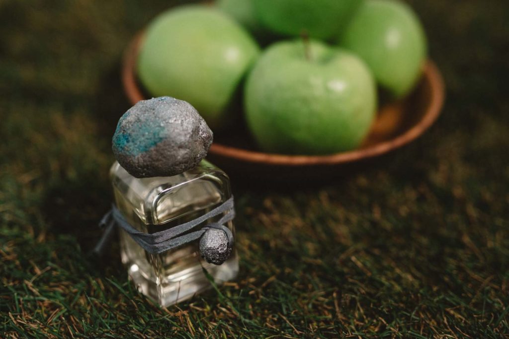 Sirio Extrait de Parfum flacon in glass bottle and hand sculpted cap and charm and green apples on the grass